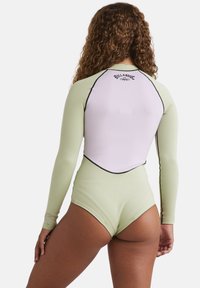 Wetsuit a maniche lunghe con un corpo verde chiaro e schiena bianca. Caratterizzato da cuciture a contrasto e un logo sulla parte superiore della schiena. Texture liscia.