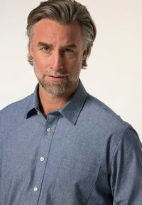 Camicia azzurro chiaro con bottoni in un tessuto testurizzato, caratterizzata da un colletto, una tasca applicata e bottoni lungo la parte anteriore.