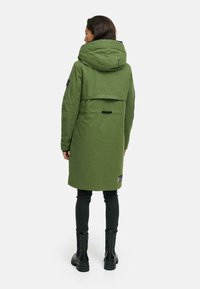 Olijfgroene parka met een grote capuchon, middellange ontwerp, zijkleppen en logo-accenten. Voorzien van een rugventilatie en verstelbare manchetten.