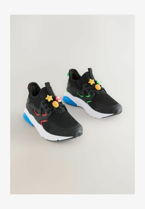 Fekete hálós tornacipők színes műanyag díszekkel és kontrasztos talp részletekkel, vörös, zöld és kék elemekkel a vizuális élmény fokozására.