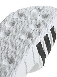 Bela guma podplata športnih copat z dvignjenimi teksturiranimi vzorci, ki ima črne akcentne barve in utore za oprijem. Ergonomična zasnova povečuje udobje.