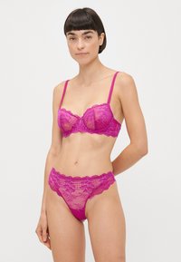 Bright pink lace bra and thong set, featuring floral patterns, scalloped edges, and adjustable straps. Semi-sheer material.
