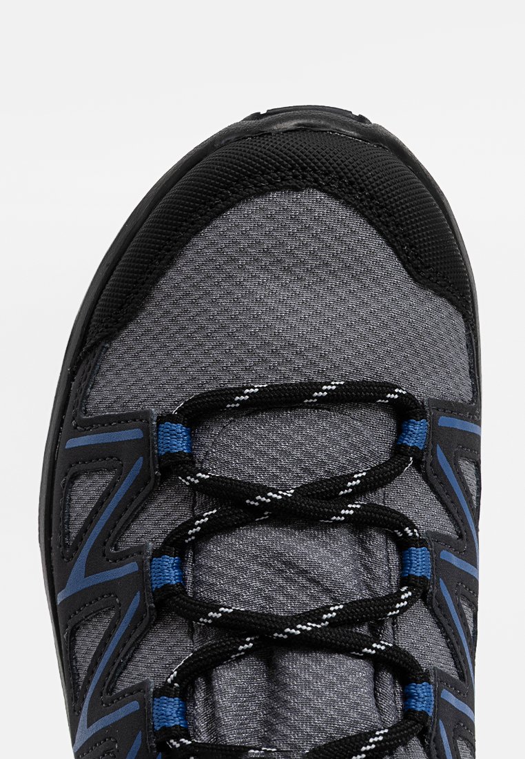 Szary but sportowy z czarnymi i niebieskimi akcentami, teksturowana cholewka i czarne sznurówki. Posiada wzmocniony nos i oddychający materiał.
