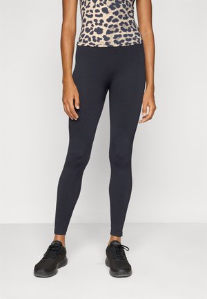 Svarta leggings i stretchmaterial med en slät yta och en smal passform. Bärs med en leopardmönstrad topp och svarta träningsskor.