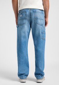 Pantaloni in denim azzurro chiaro con una vestibilità rilassata, caratterizzati da numerose tasche, cuciture visibili e polsini a gamba affusolata alla caviglia.