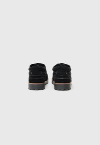 Schwarze Wildlederschuhe mit niedrigem Profil, Gummisohle und stickdetail. Verfügt über zwei Ösen für Schnürsenkel hinten.
