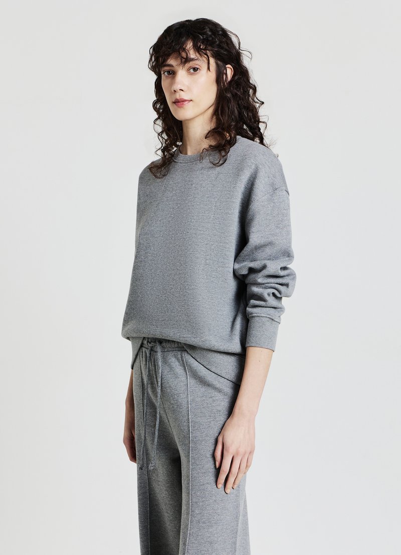 Felpa grigia con una trama morbida, caratterizzata da un collo rotondo e una vestibilità rilassata. Abbinata a pantaloni grigi con coulisse per un look coordinato.