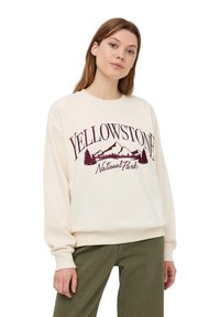 Felpa color crema con la scritta "Parco Nazionale YELLOWSTONE" in bordeaux, accompagnata da grafiche di montagne e alberi. Design a vestibilità ampia.