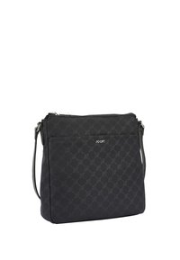 Borsa a spalla nera con tessuto a fantasia, chiusura a zip e tracolla regolabile. Presenta una tasca frontale e un dettaglio del logo. Design compatto e rettangolare.