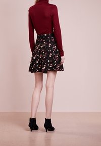 Bordeaux turtleneck, hameau noir à motif floral, design évasé, et bottines noires. Texture lisse, corsage moulant, et ourlet mi-genou.