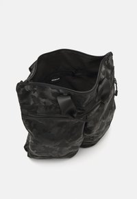 Czarna torba w wzór moro z podwójnymi uchwytami, zapięciem na zamek błyskawiczny i wewnętrzną kieszenią. Wykonana z teksturowanego materiału syntetycznego.