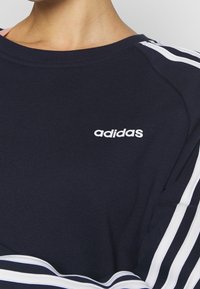 Sudadera Adidas en color navy con rayas blancas en las mangas y el logo de Adidas impreso en el pecho.