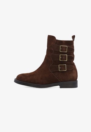 Brown suede ankle boot with a rounded toe, three decorative buckles, and a low stacked heel. Textured surface and sleek design.