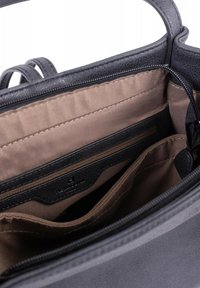 Intérieur d'un sac à main en cuir noir avec une doublure en tissu beige, comprenant une poche zippée et deux compartiments ouverts. Textures subtiles visibles.