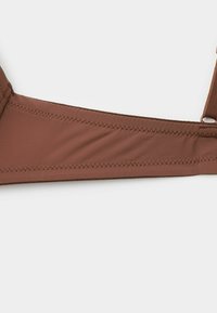 Bruine stoffen bralette met een naadloos ontwerp, voorzien van verstelbare bandjes en een zachte, gladde textuur. Minimaal zichtbare stiksels.