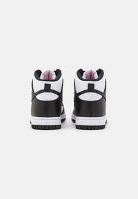 Sneaker alte in bianco e nero con materiale in pelle liscia, collo imbottito e suola in gomma a contrasto. Presentano elementi di design minimalista.