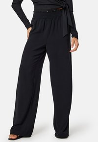 Zwarte wijde broek van zacht materiaal, met een elastische tailleband voor comfort en een relaxte pasvorm, geschikt voor casual kleding.