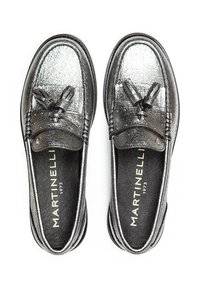 Mocasines plateados metálicos con un acabado texturizado, que presentan un lazo en la parte delantera y un interior negro con una marca dorada.