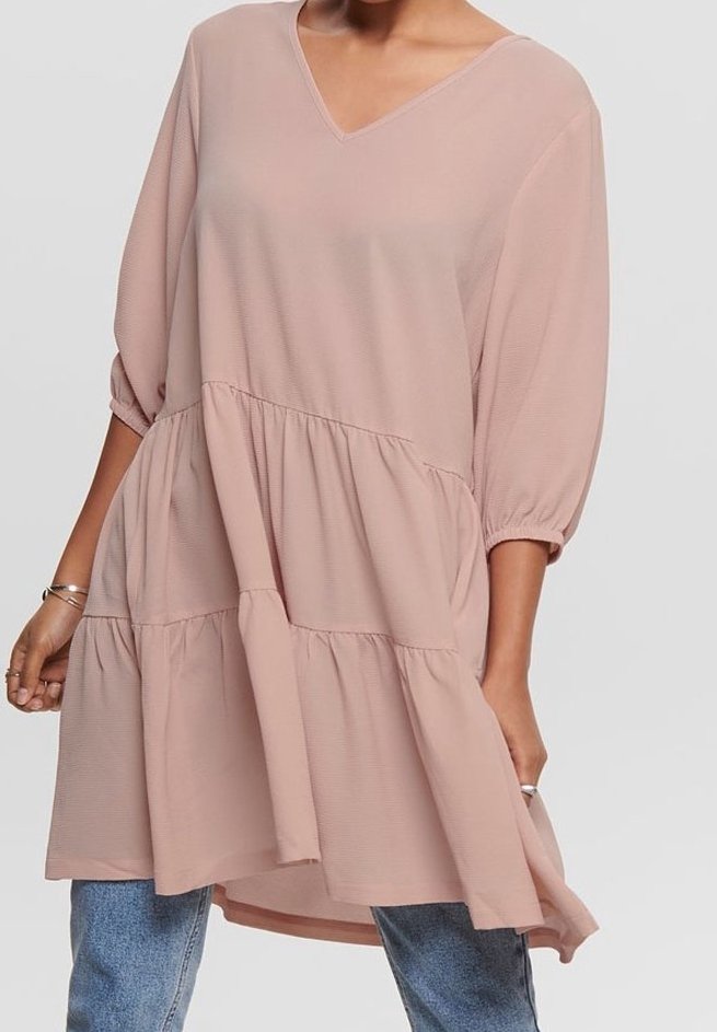 Robe ample rose poudré à col en V avec des manches bouffantes trois-quarts et un ourlet à volants superposés portée sur un jean bleu.
