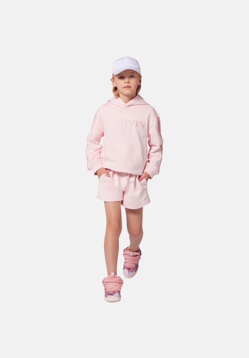 Haut à capuche rose avec logo "LANVIN" en relief, shorts roses assortis et baskets à motifs roses et violets. Une casquette blanche complète la tenue.
