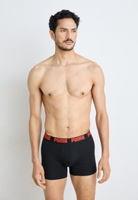 Boxeri negri cu logo roșu "PUMA" pe banda elastică, cu un design ajustat și material moale. Modelul stă cu încredere.