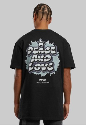 Black cotton t-shirt featuring a large graffiti-style print on the back with "PEACE AND LOVE" in white and light blue, an accent star above.