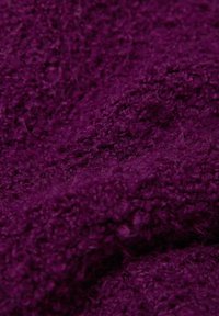 Purple textured fabric showcasing a fuzzy surface with a rich, deep hue, highlighting its soft, woven appearance and uneven plushness.