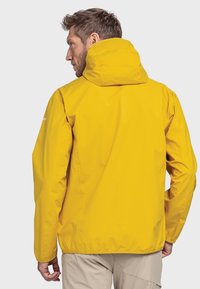 Gelbe wasserfeste Jacke mit Kapuze, ausgestattet mit einer glatten Textur und elastischen Bündchen, entworfen für den Einsatz im Freien. Rückansicht gezeigt.