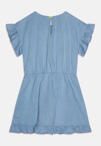 Denimkjole med korte volangermer, elastisk liv, og volangkant med rosa søm. Bak lukkingen har en grønn knapp.