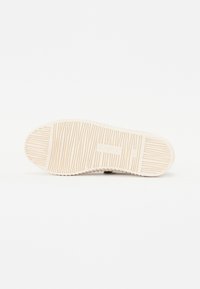 Semelle de chaussure avec un motif texturé, comportant des rainures et des crêtes en caoutchouc beige clair. Marquée du nom de la marque "Cabbot."