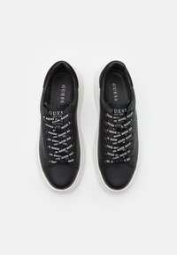 Schwarze Leder-Sneaker mit einem Slip-On-Design, ausgestattet mit elastischen Schnürsenkeln und einer weißen Gummisohle. "GUESS"-Logo auf den Schnürsenkeln aufgedruckt.