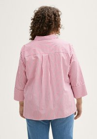 Camicia a righe con strisce verticali rosa e bianche, maniche a tre quarti, una piega sul retro e colletto a revers.