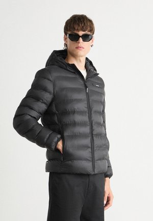 Giubbotto piumino nero con cappuccio, caratterizzato da un design trapuntato e una chiusura frontale con zip. La finitura testurizzata conferisce calore e un aspetto elegante.