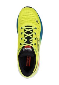 Zapatilla deportiva verde lima con parte superior de malla, acentos en negro, cordones redondos y suela blanca. Presenta la marca "Skechers" en el costado y en el talón.