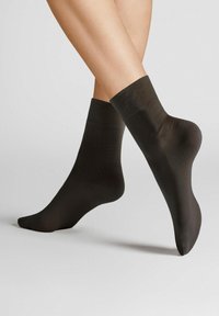Schwarze Knöchelsocken aus glattem, dehnbarem Material. Einfaches Design mit einer Höhe bis zur Mitte der Wade und ohne sichtbare Muster oder Akzente.