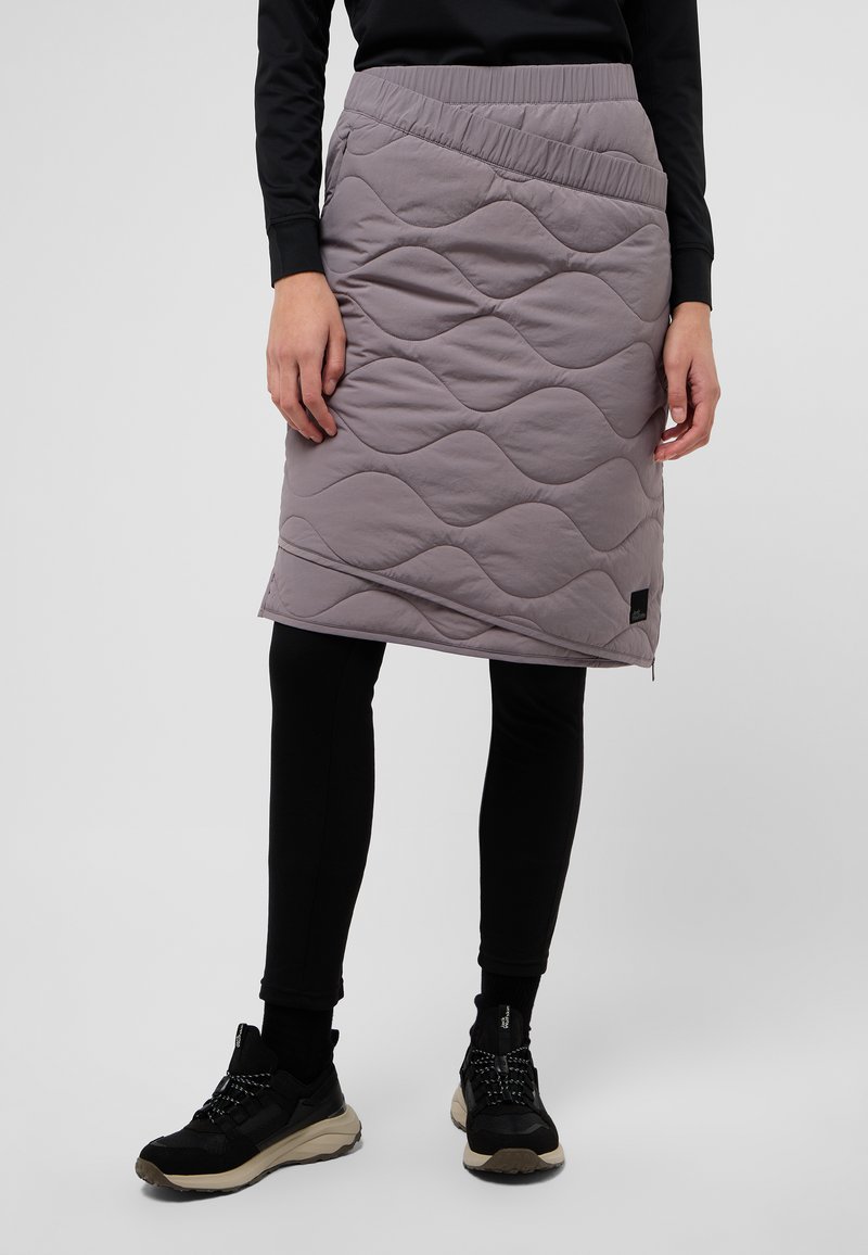 Gequiltede grijze rok met een gestructureerd golfpatroon, voorzien van een elastische tailleband en een zijrits, gedragen over zwarte leggings en sneakers.