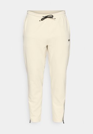 Joggers de color beige claro con cintura elástica y cordón, que cuentan con bolsillos laterales y puños con cremallera para un ajuste ceñido.