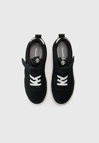 Sorte semskede sneakers med hvite lisser og borrelås. Har gummisåle og merke på tungen, med en rund tådesign.