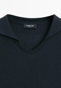 Mörkblå V-ringad tröja med ribbad textur och uppvikt krage. Har en etikett med texten "Massimo Dutti". Tillverkad av stickat tyg.