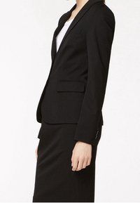 Svart kavaj med en strukturerad design, enkelknappslås, slagkrage och två framfickor. Tillverkad av ett slitstarkt tyg.