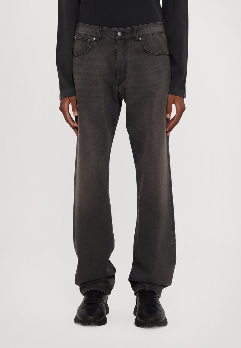 Tamno sive traperice ravnog kroja, s dizajnom od pet džepova i suptilnim izblijeđenjem. Imaju metalno dugme i zatvarač.