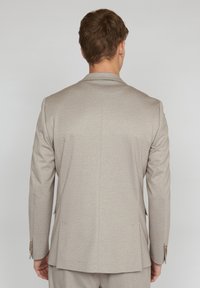 Light beige suit jacket with a textured pattern, single-breasted design, notched lapels, two back vents, and metal-button accents.