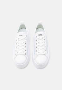 Hvite joggesko med glatt syntetisk overdel, flate lisser, sølvfarget merkevare og teksturert sidepanel. Har rund tå og tykk såle.