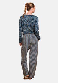 Blauw bloemenprint lange mouw top in combinatie met gestreepte, wijde broek in marineblauw, oranje en crème. Soepele stof met een comfortabele pasvorm.