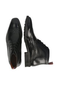 Zapatos de vestir de cuero negro con diseño brogue, punta afilada, cierre con cordones y acentos texturizados. Lengüeta vibrante en el talón.