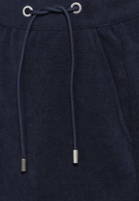 Marineblaue Jogginghose mit geripptem Bund, ausgestattet mit einem Kordelzug mit metallischen Enden und zwei seitlichen Taschen.