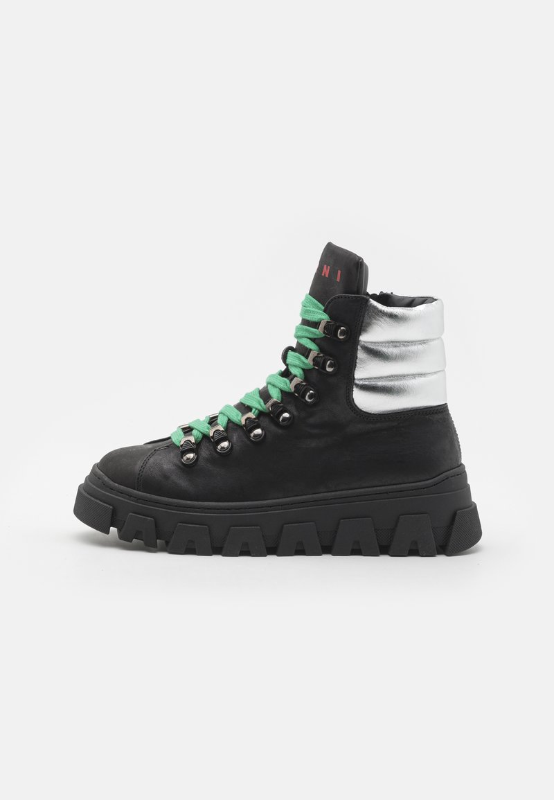 Höga sneakers i svart läder med en silverfärgad vadderad krage, gröna snören och en kraftig svart gummisula med distinkta spår.