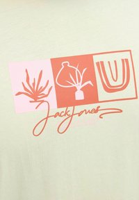 Lys grøn t-shirt med trykte grafikker i pink og koral, inklusive plantemotiver og "Jack Jones" tekst i kursiv skrifttype.