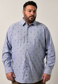 Camisa abotonada azul claro con un pequeño estampado floral, mangas largas y una tela texturizada, con puños redondeados y botones marrones.