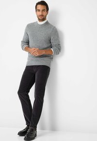 Grå strikket sweater med ribbet krave og kant, parret med sorte fløjl bukser. Sorte lædersko fuldender outfittet.